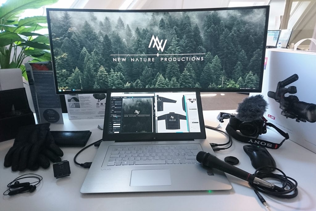 Design oppsett med kamera mikrofon og annet utstyr som ligger på et bord med en monitor som viser grafisk design
